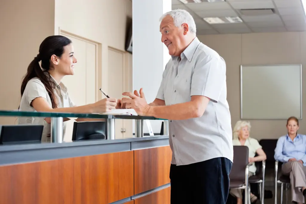 Patient speaking with a receptionist at a medical clinic front desk