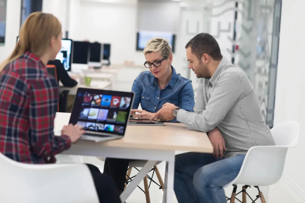 Three colleagues reviewing a website design on a laptop